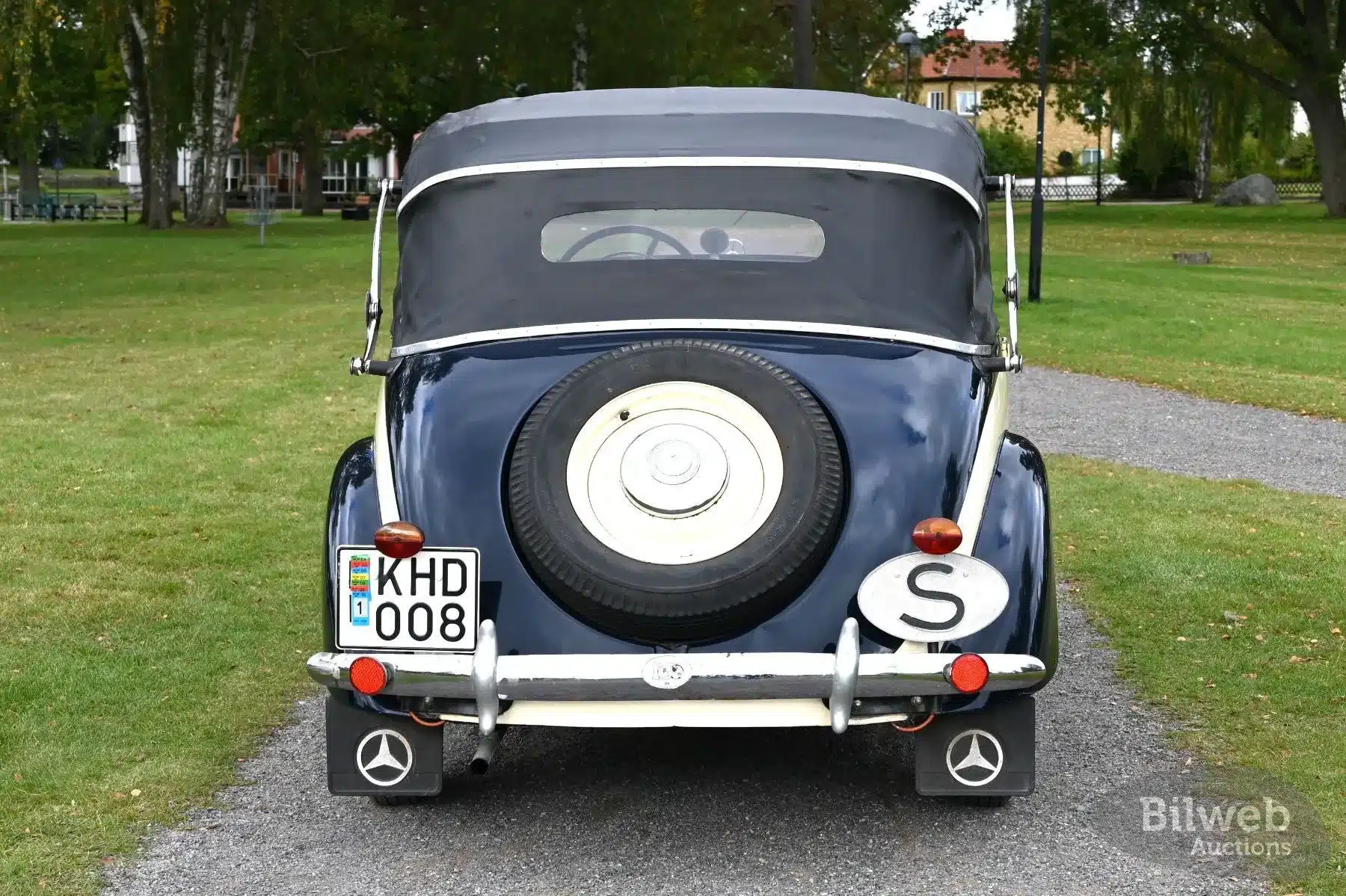 Rückseite eines dunkelblauen Mercedes-Benz 170 V Cabriolet von 1939 mit Reserverad und geschlossenem Verdeck im Grünen.