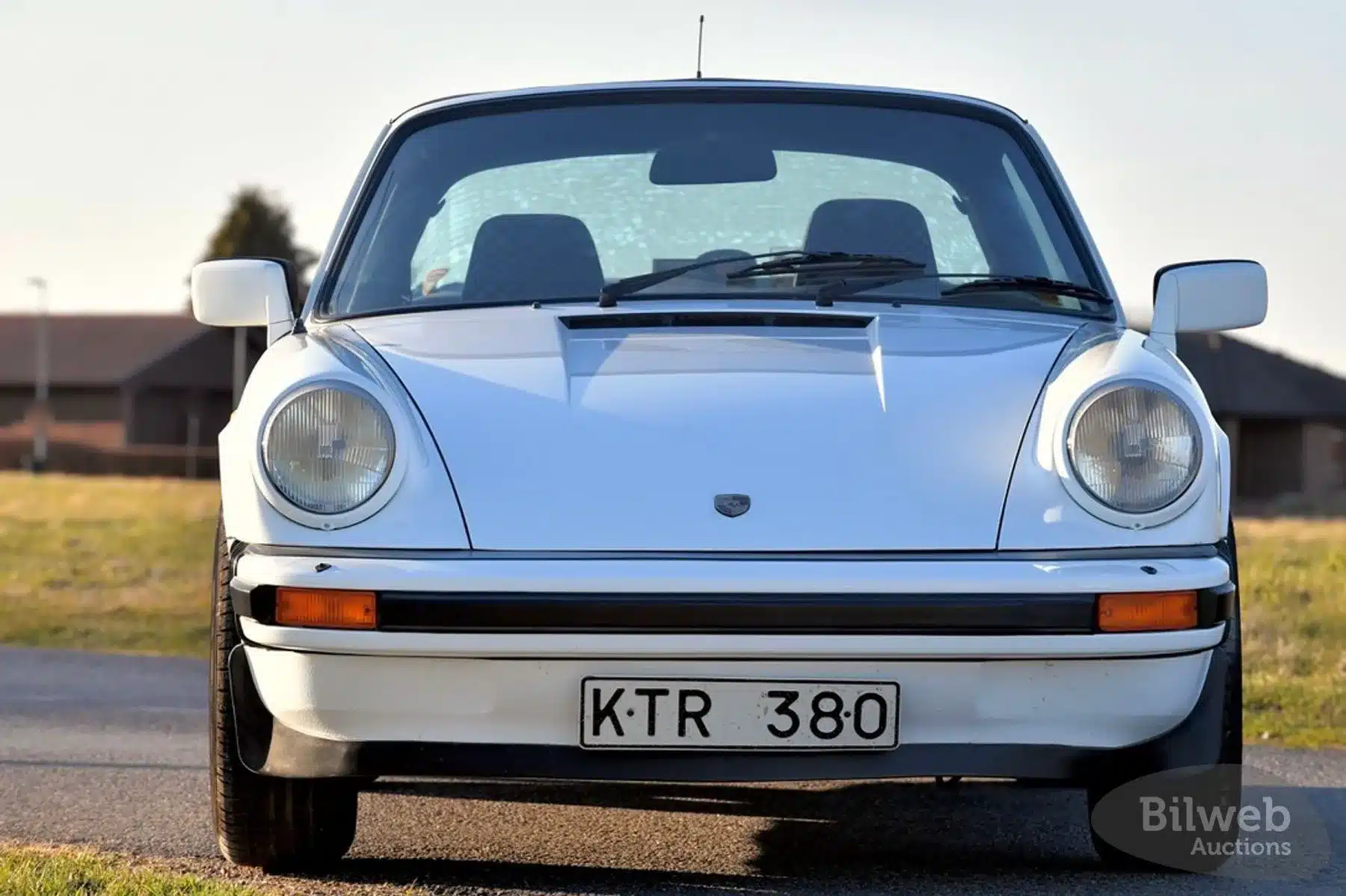 Weiße Frontansicht eines Porsche 911 SC Targa 3,0, Baujahr 1981, auf einer Straße, aufgenommen bei Tageslicht.