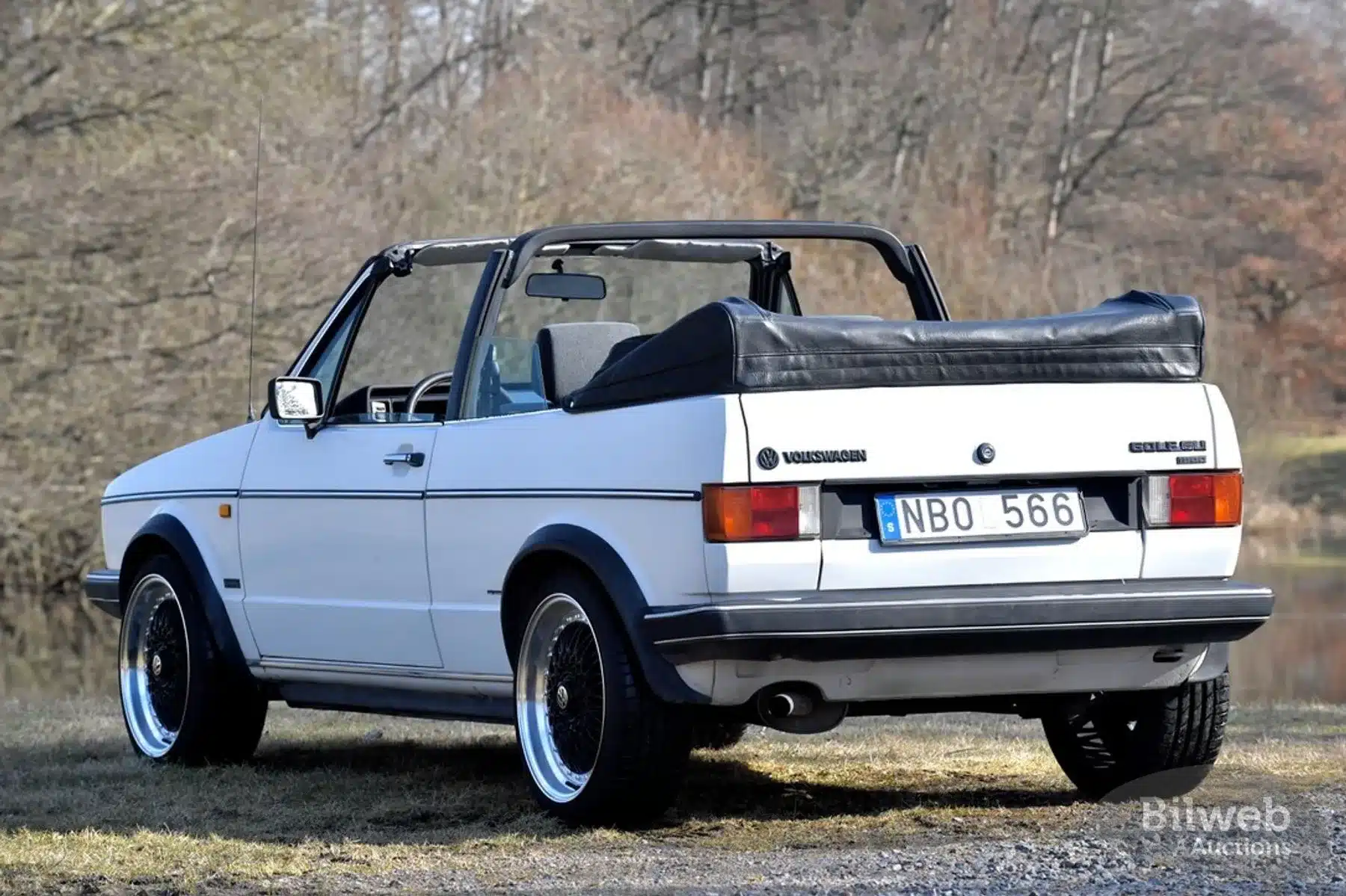 Weißes VW Golf Mk I Cabriolet, Baujahr 1986, von hinten fotografiert, mit offenem Verdeck und charakteristischen Gebrauchsspuren.
