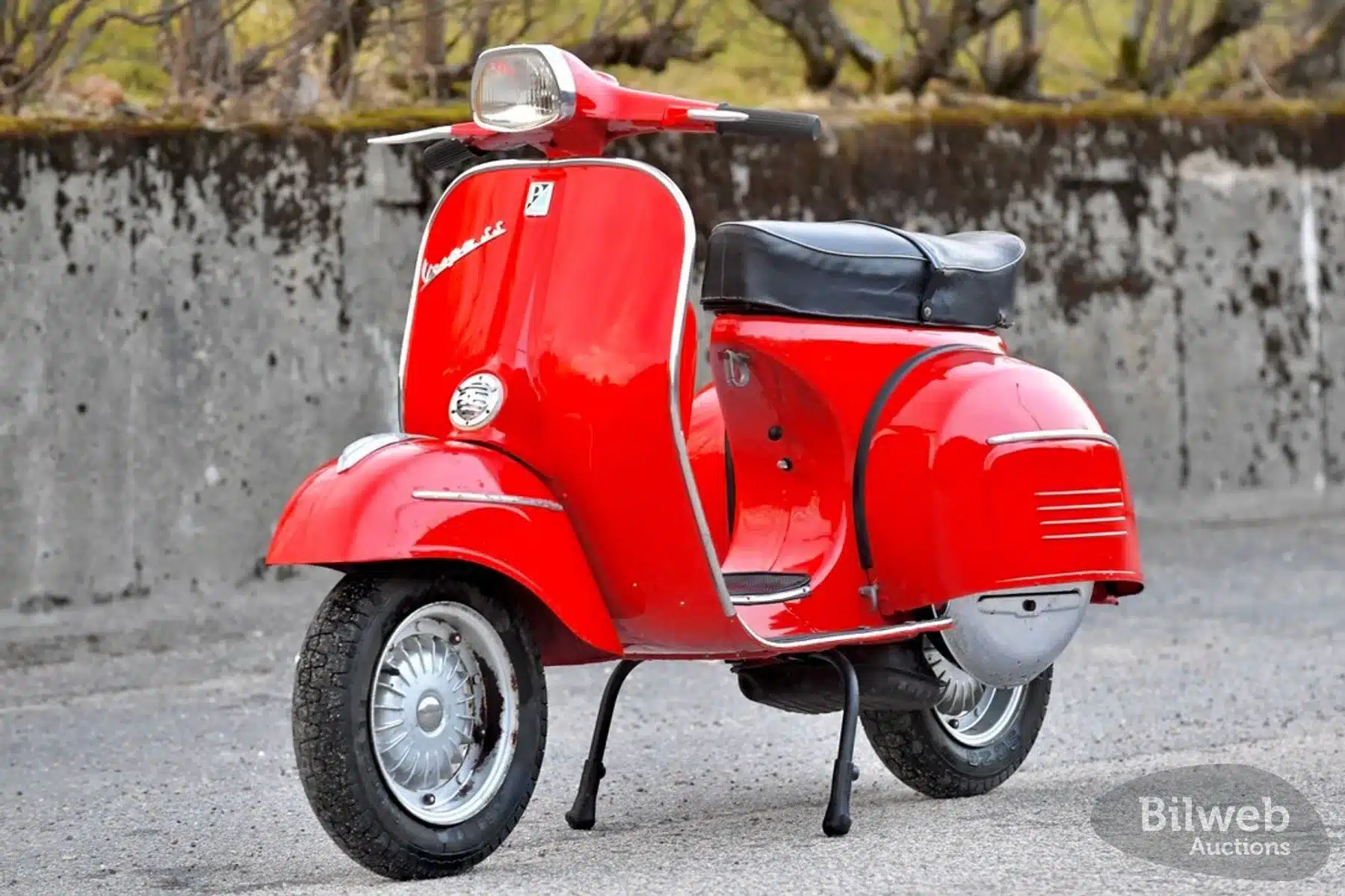 Rote Vespa 180 Super Sport von 1966, seitlich fotografiert, auf Asphalt stehend.