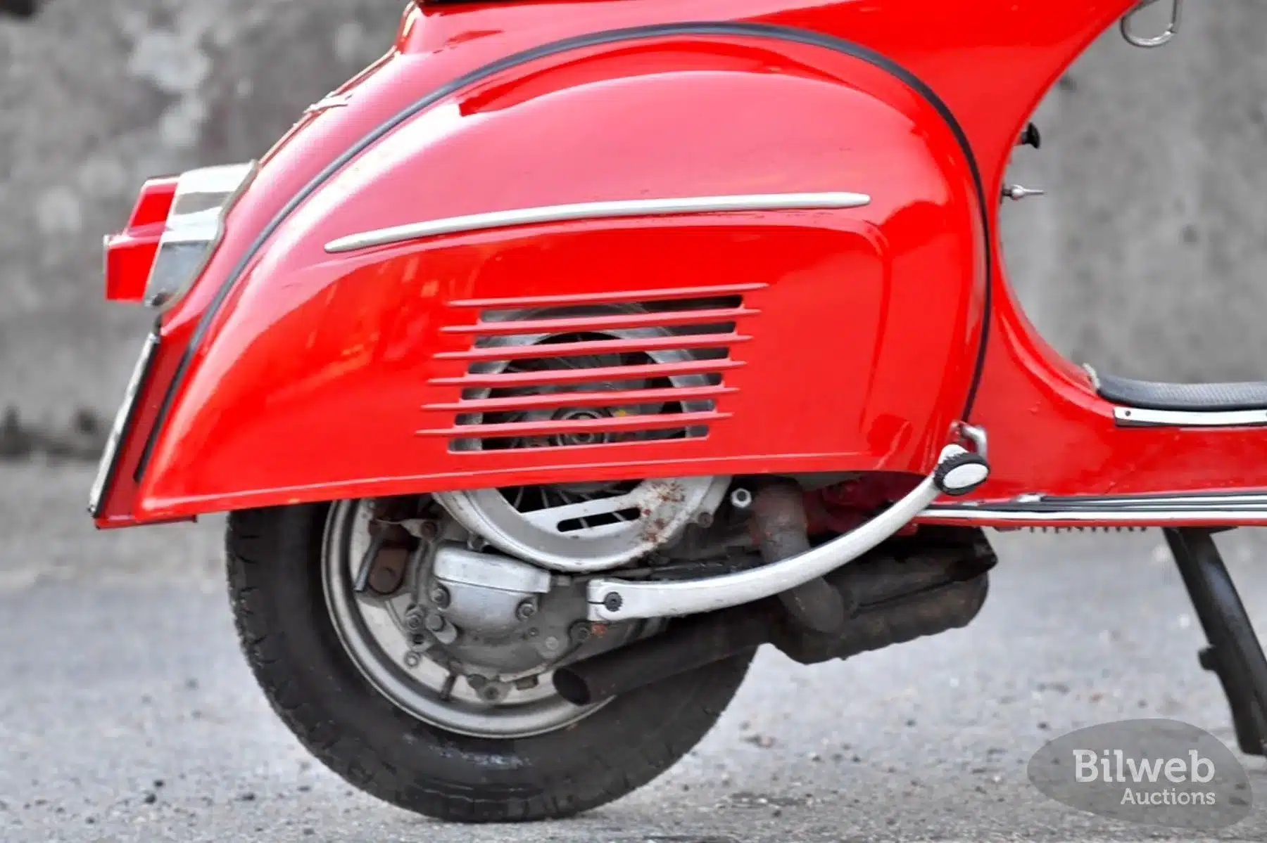 Nahaufnahme des Motors und der hinteren Seitenverkleidung einer roten Vespa 180 Super Sport von 1966