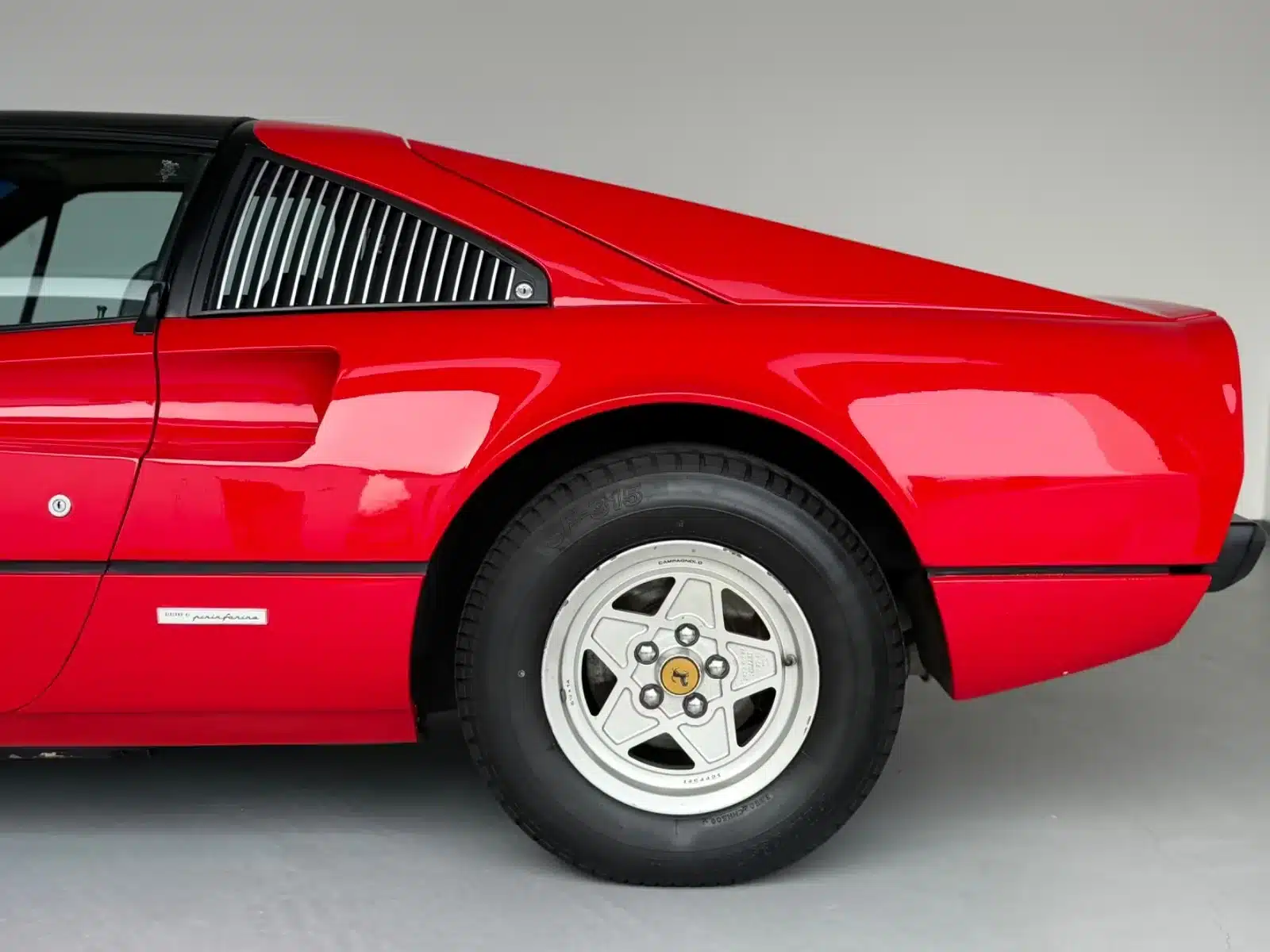 Heck und Hinterrad eines roten Ferrari 308 GTSi mit typischer Pininfarina-Linienführung