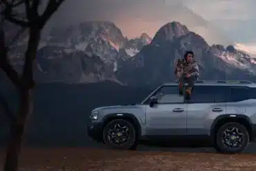 JETOUR T2 i-DM SUV mit Panoramadach, Mann mit Hund auf dem Dach, Berge im Hintergrund bei Sonnenuntergang.