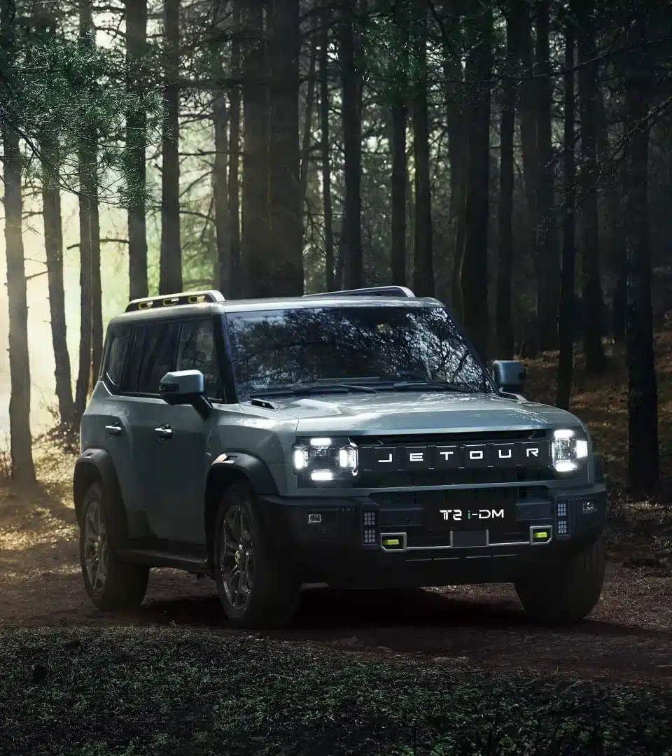 JETOUR T2 i-DM SUV fährt über einen Waldweg, robustes Design mit kantigen Linien und moderner Lichtsignatur.