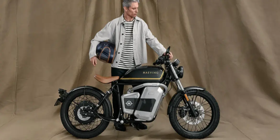 Maeving RM1S Elektromotorrad mit Mann, der einen Helm hält, im Studio