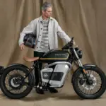Maeving RM1S Elektromotorrad mit Mann, der einen Helm hält, im Studio