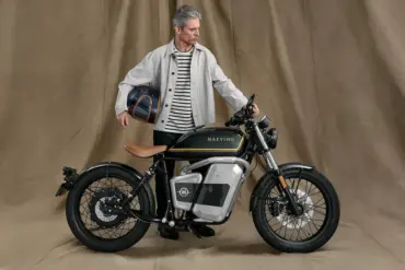 Maeving RM1S Elektromotorrad mit Mann, der einen Helm hält, im Studio