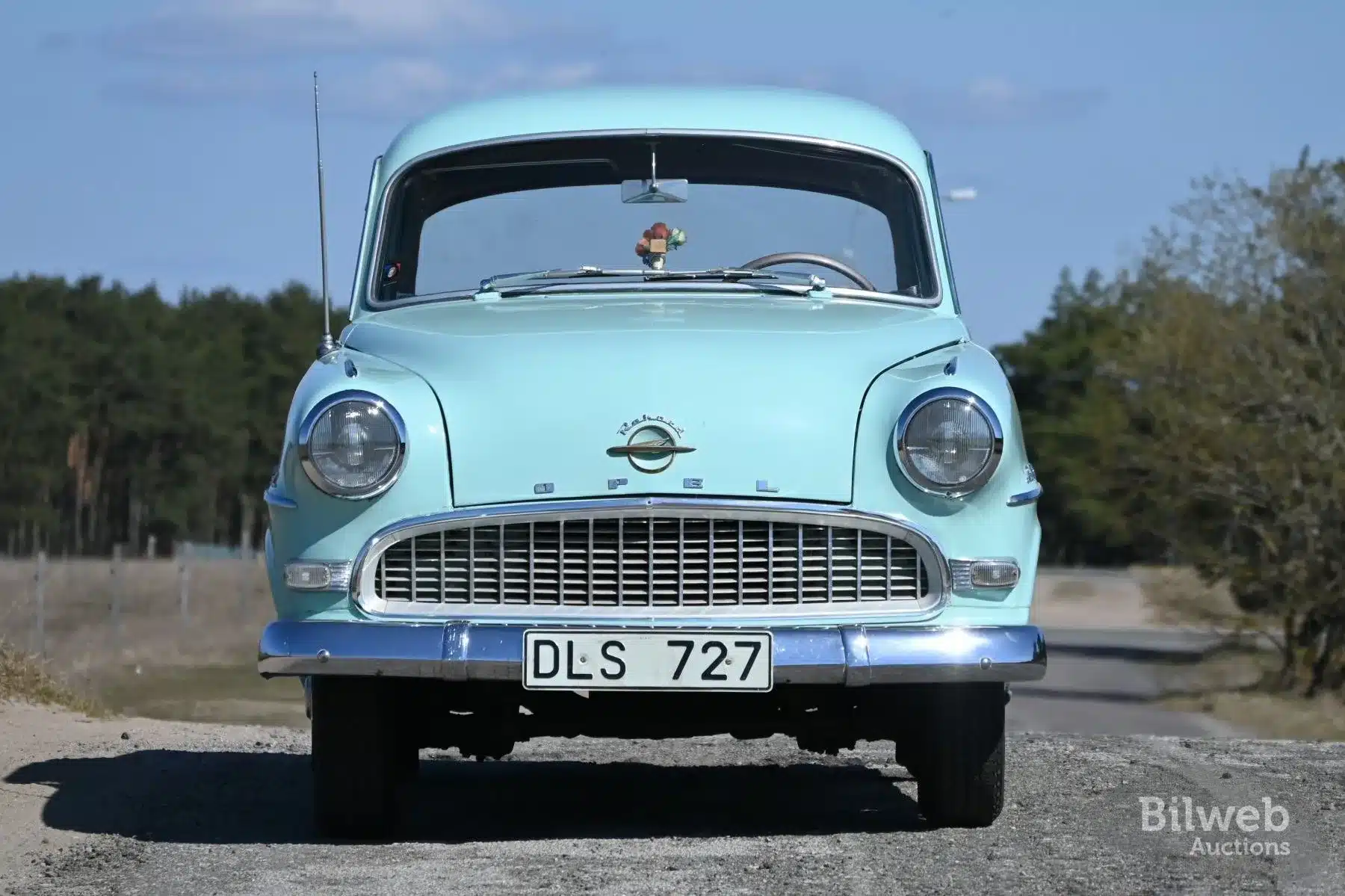 Frontansicht eines Opel Olympia Rekord 1,5 von 1956 in Hellgrün auf einer Landstraße.