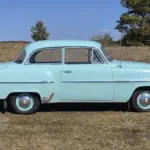 Opel Olympia Rekord 1,5, Baujahr 1956, hellgrün, Seitenansicht auf freiem Feld.