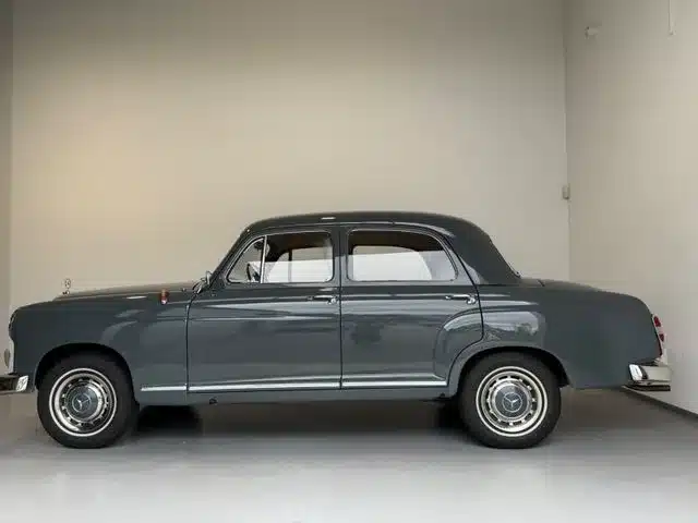 Seitenansicht eines grauen Mercedes-Benz 180 Ponton der 1950er Jahre in einer modernen Garage.