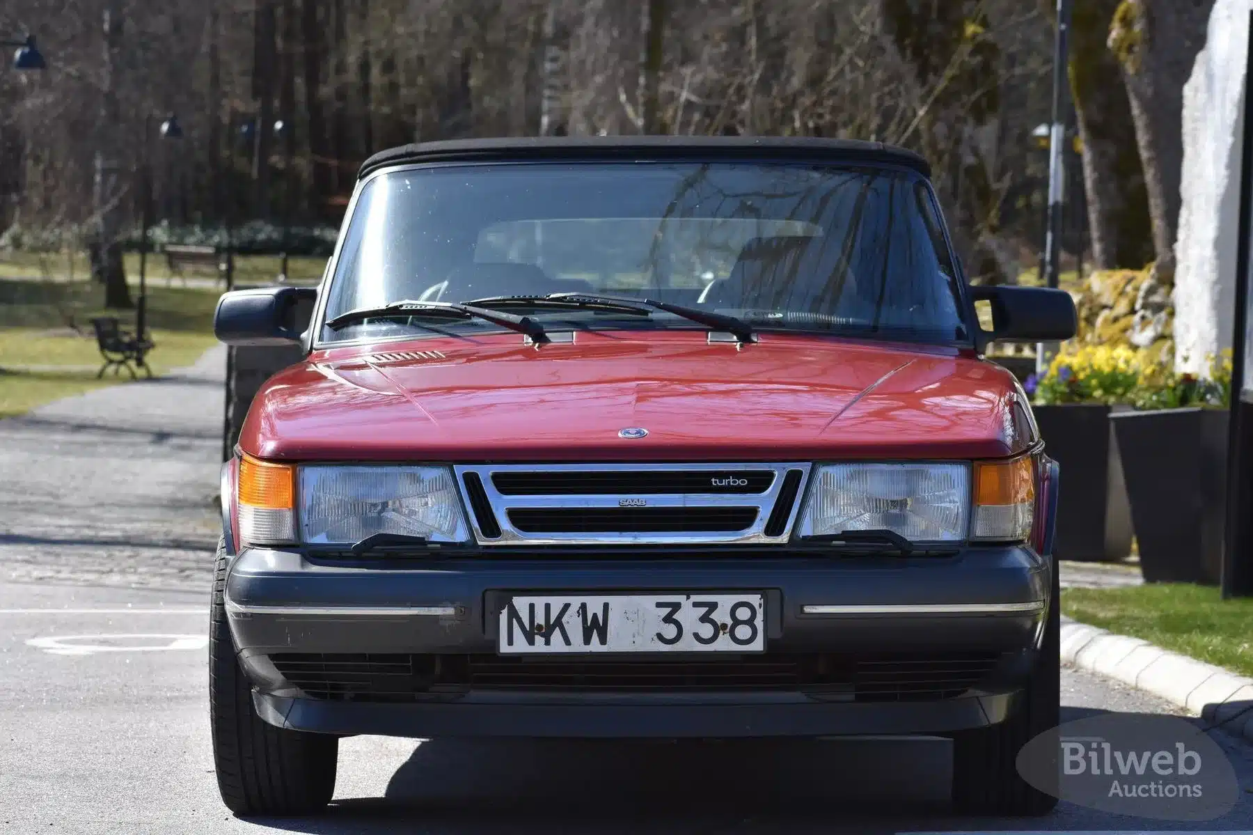 Roter Saab 900 T16 Cabriolet 2.0 16V Turbo von 1988 aus der Frontperspektive, fotografiert im Freien.
