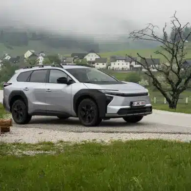 Silberner Toyota bZ4X Touring als Elektro-SUV auf einer Landstraße in bergiger und bewaldeter Umgebung