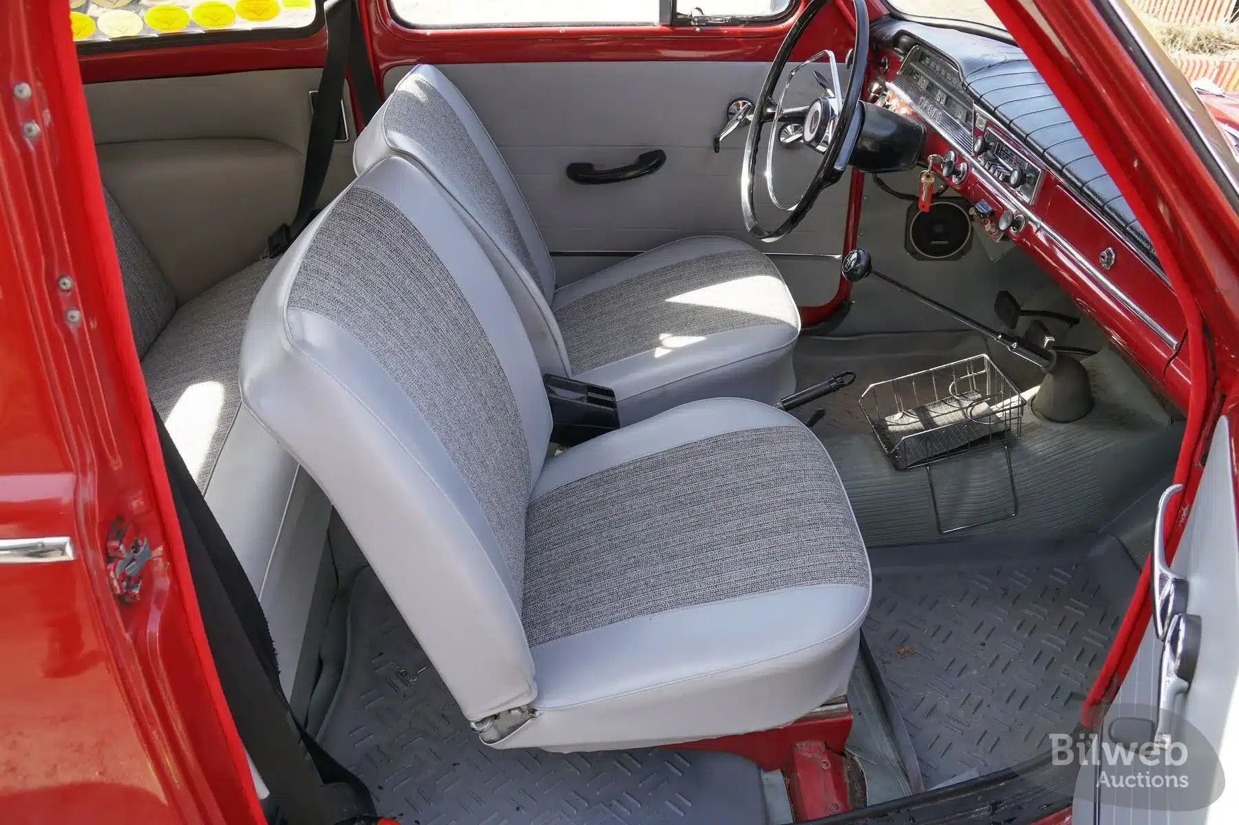 Innenraum eines roten Volvo PV 544 Sport mit grauen Sitzen und klassischer Schalteinheit, Baujahr 1962.