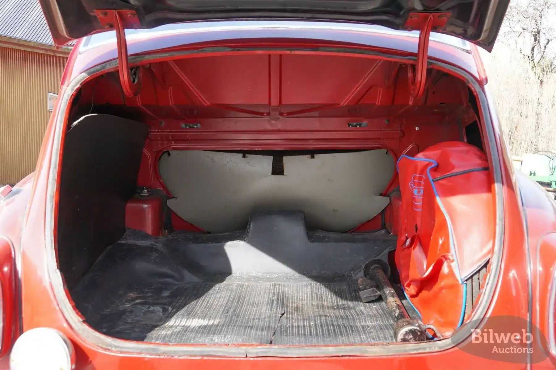 Geöffneter Kofferraum eines roten Volvo PV 544 Sport von 1962, mit Ersatzrad in roter Hülle und Werkzeug.