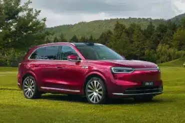 Roter Wenjie M7 SUV auf einer Wiese mit Bäumen und Bergen im Hintergrund.