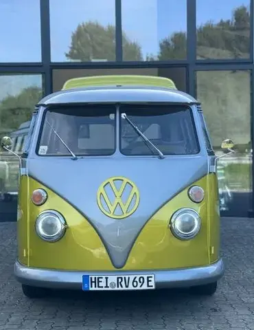 Frontalansicht eines gelb-grauen VW T1 Bulli, restauriert und elektrisch umgebaut, vor einem Autohaus