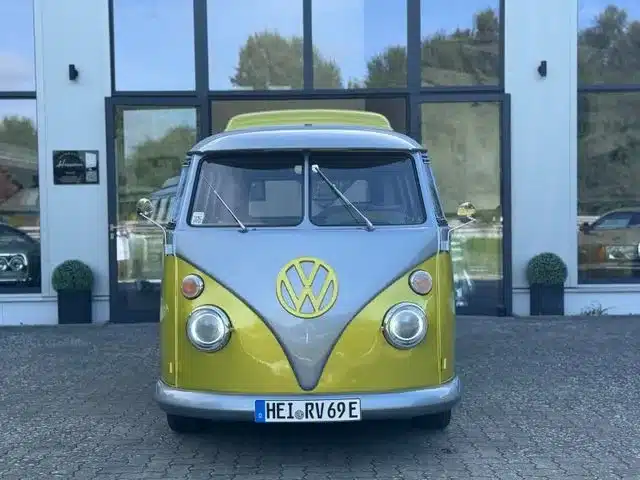 Frontalansicht eines gelb-grauen VW T1 Bulli, restauriert und elektrisch umgebaut, vor einem Autohaus