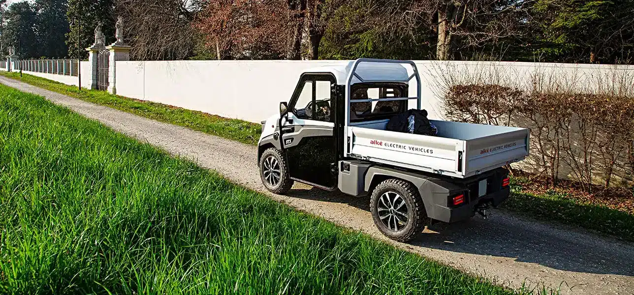 Elektrischer Alke ATX 440S Transporter fährt auf einem schmalen Weg an einer Mauer entlang