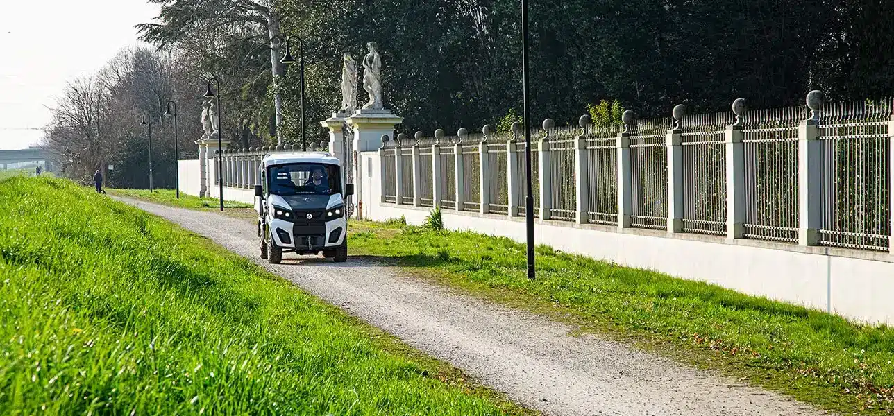 Elektrisches Nutzfahrzeug Alke ATX 440S fährt auf schmalem Weg neben einem Zaun.