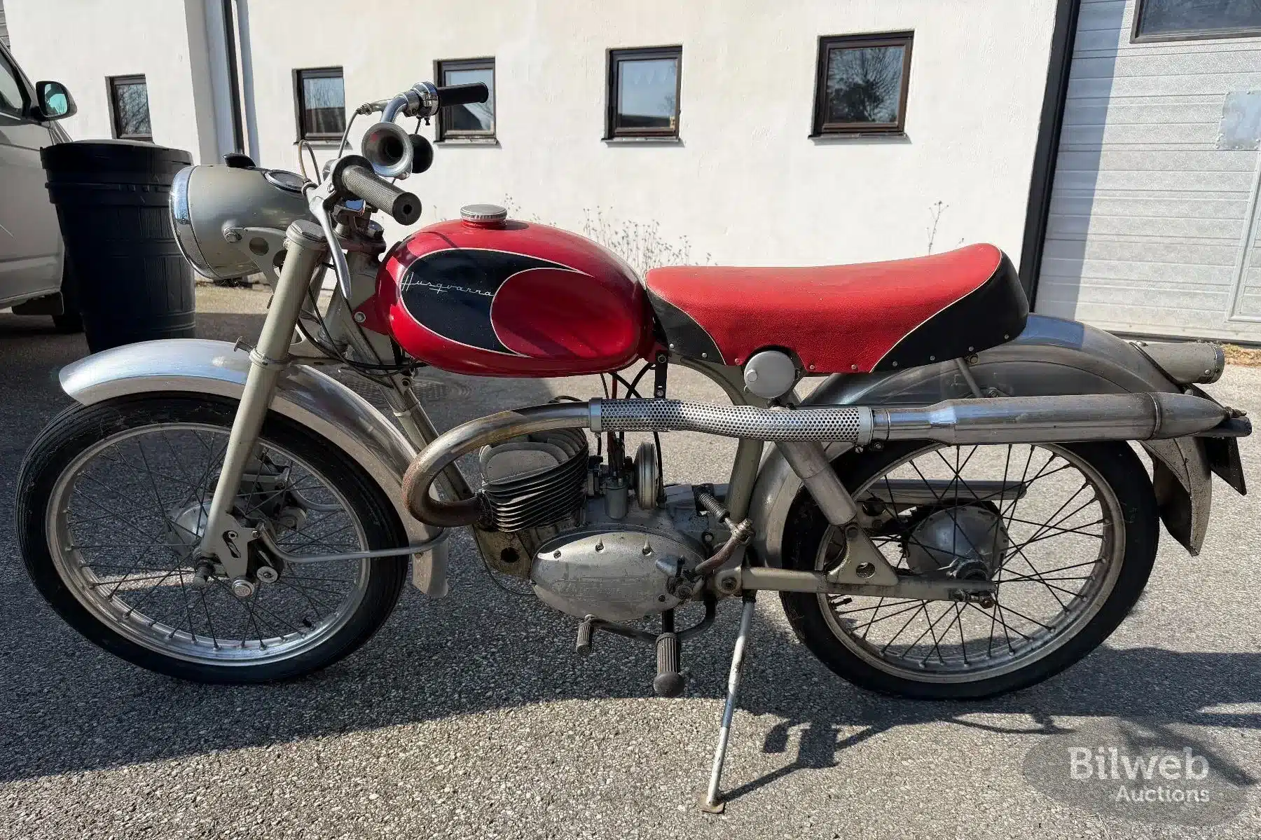 Seitenansicht einer Husqvarna 282 E Silverpil von 1960 in Originalausführung mit rotem Sitz und Tank, aufgenommen im Freien.