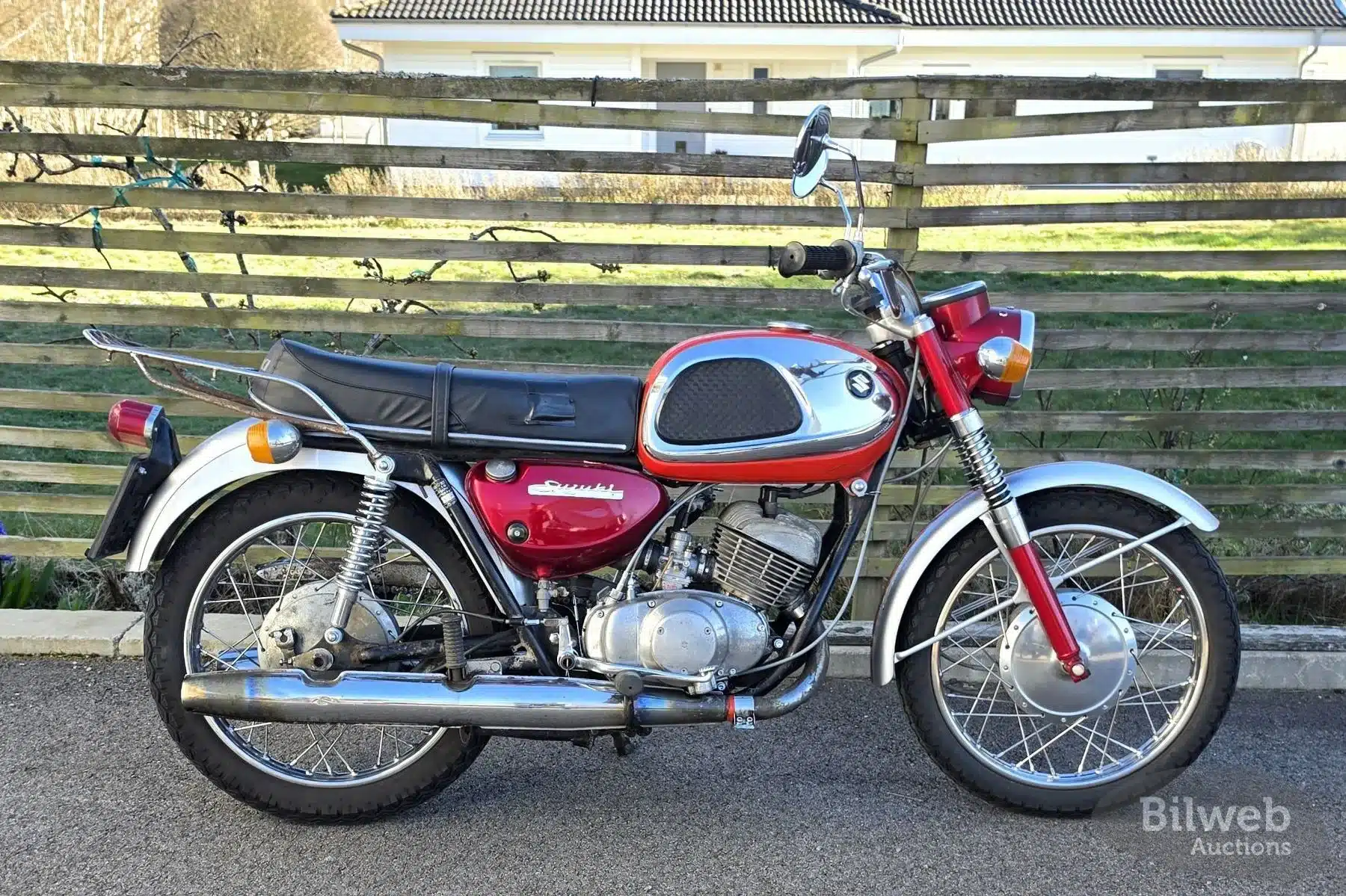 Seitenansicht einer Suzuki T20 von 1969 mit rotem Tank, sichtbarer Patina und originalen Anbauteilen