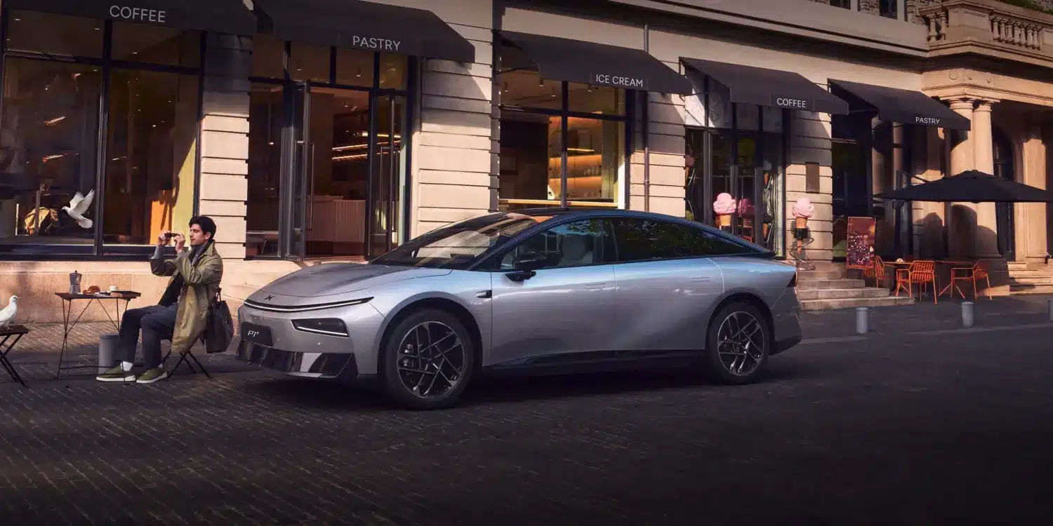 Der XPENG P7+ in Silber geparkt vor einem Straßencafé.