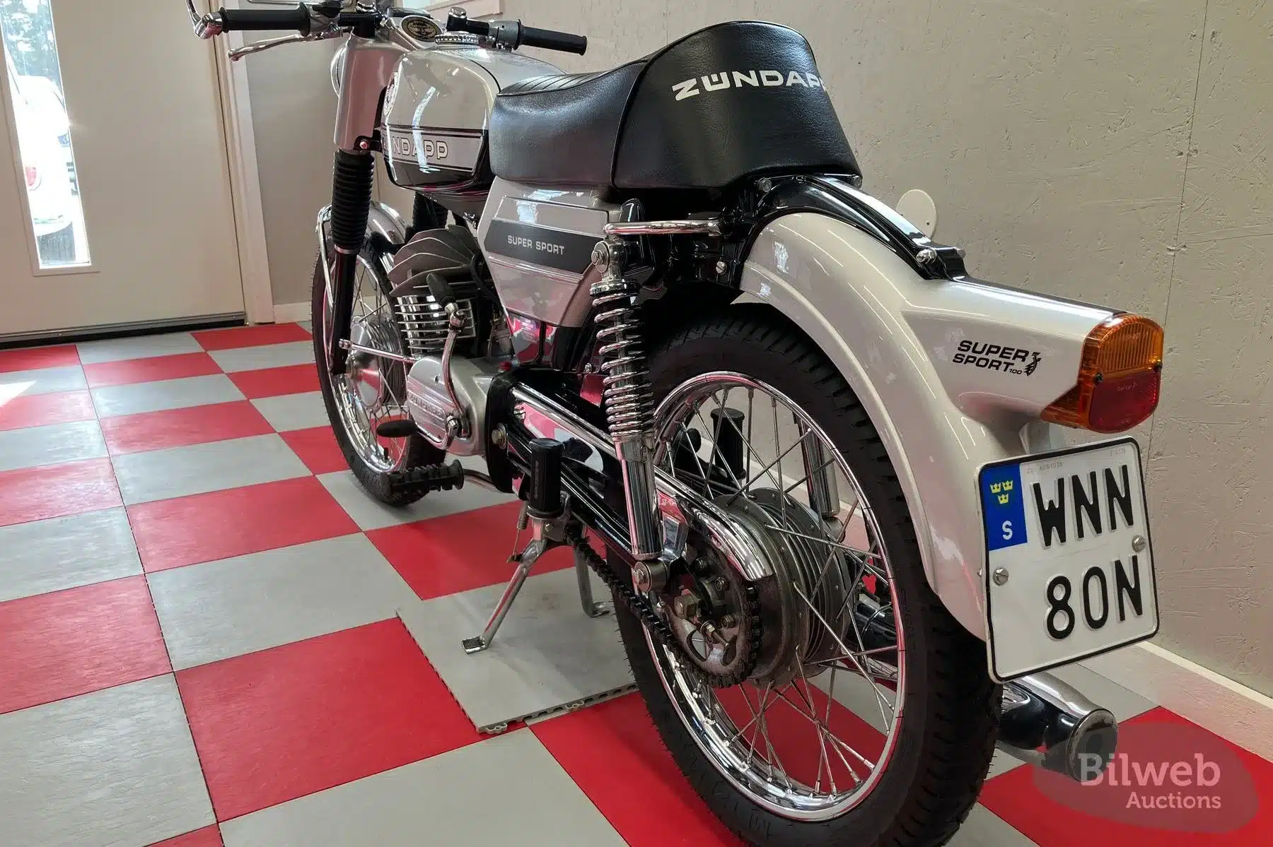 Restaurierte Zündapp KS 125 von 1970, als Café Racer im Stil der 70er Jahre, im Showroom auf rotem Schachbrettboden.