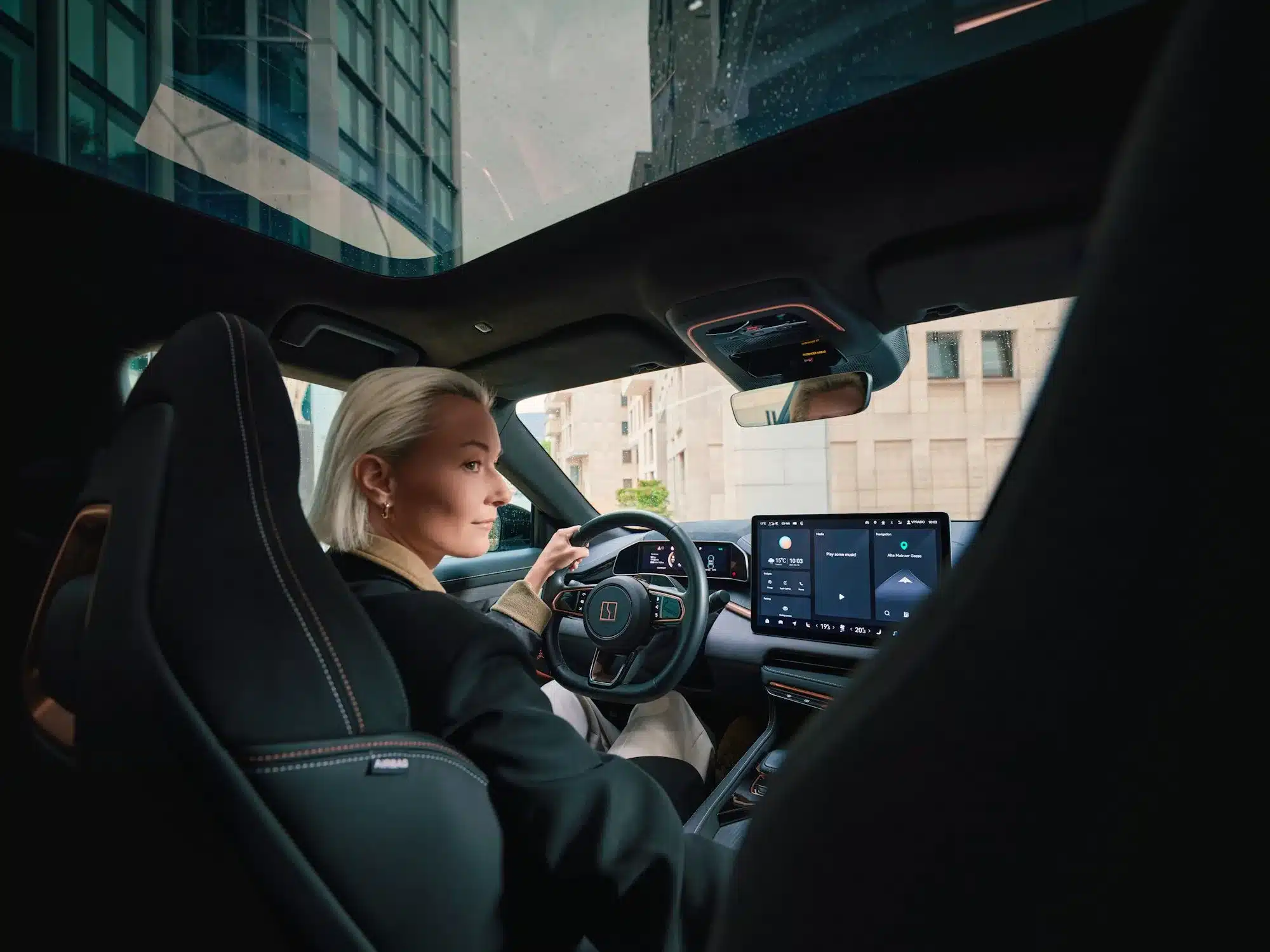 Fahrerin sitzt im modernen Innenraum eines ZEEKR 001 mit großem Panoramadach und digitalen Displays
