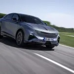 Die Alpine A390 GTS in grau fährt dynamisch auf einer Landstraße, aufgenommen bei Tageslicht.