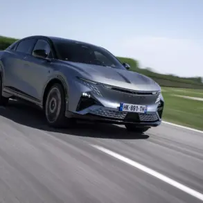 Die Alpine A390 GTS in grau fährt dynamisch auf einer Landstraße, aufgenommen bei Tageslicht.