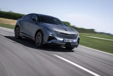 Die Alpine A390 GTS in grau fährt dynamisch auf einer Landstraße, aufgenommen bei Tageslicht.