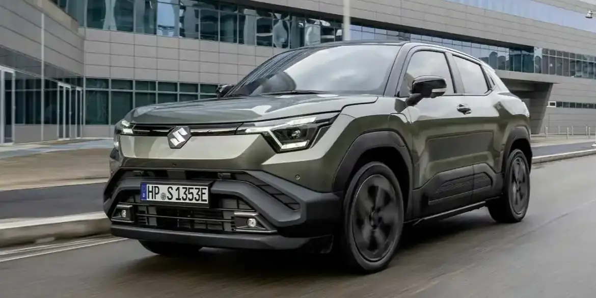 Suzuki e VITARA als vollelektrisches SUV in grün vor einem Bürogebäude, Frontansicht.