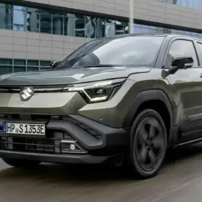 Suzuki e VITARA als vollelektrisches SUV in grün vor einem Bürogebäude, Frontansicht.