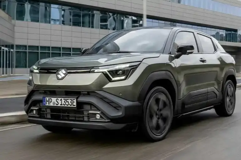 Suzuki e VITARA als vollelektrisches SUV in grün vor einem Bürogebäude, Frontansicht.