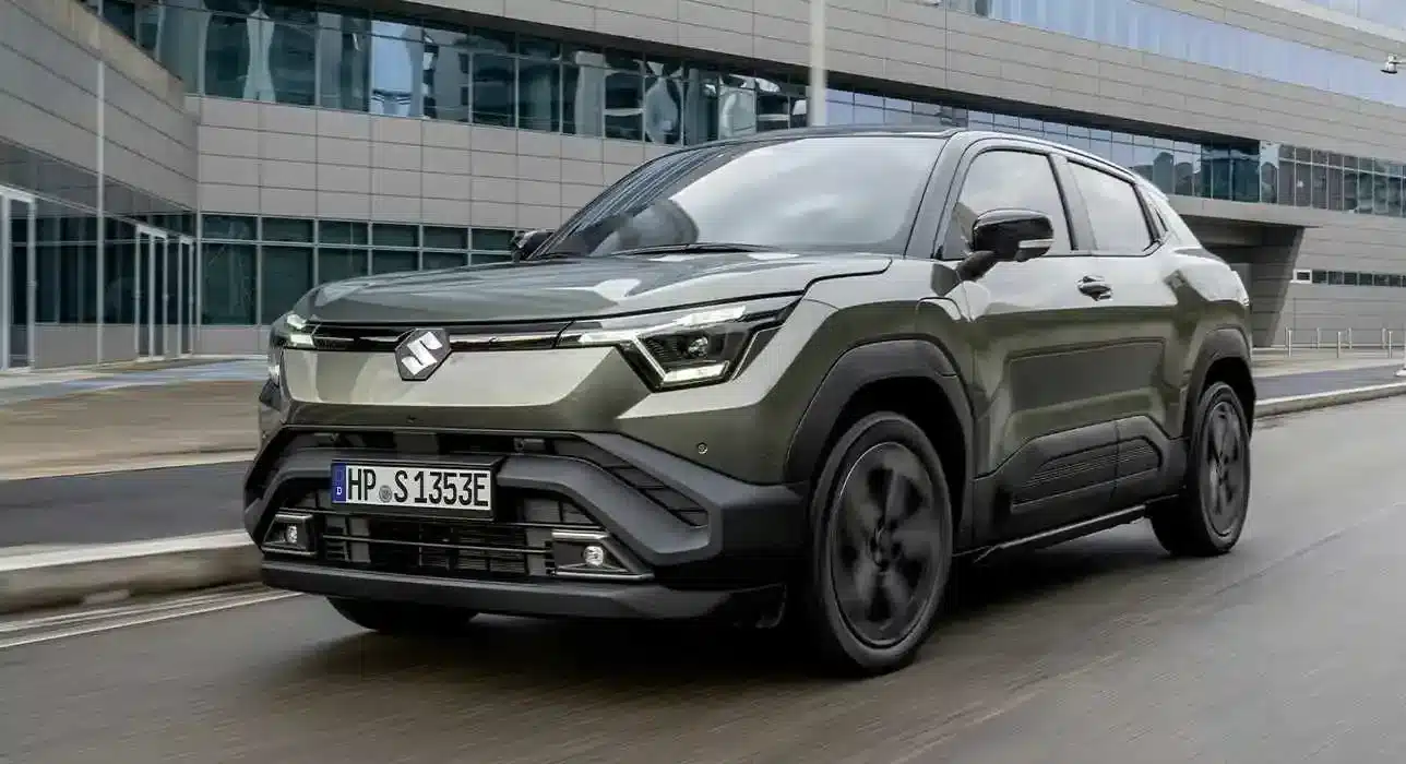 Suzuki e VITARA als vollelektrisches SUV in grün vor einem Bürogebäude, Frontansicht.