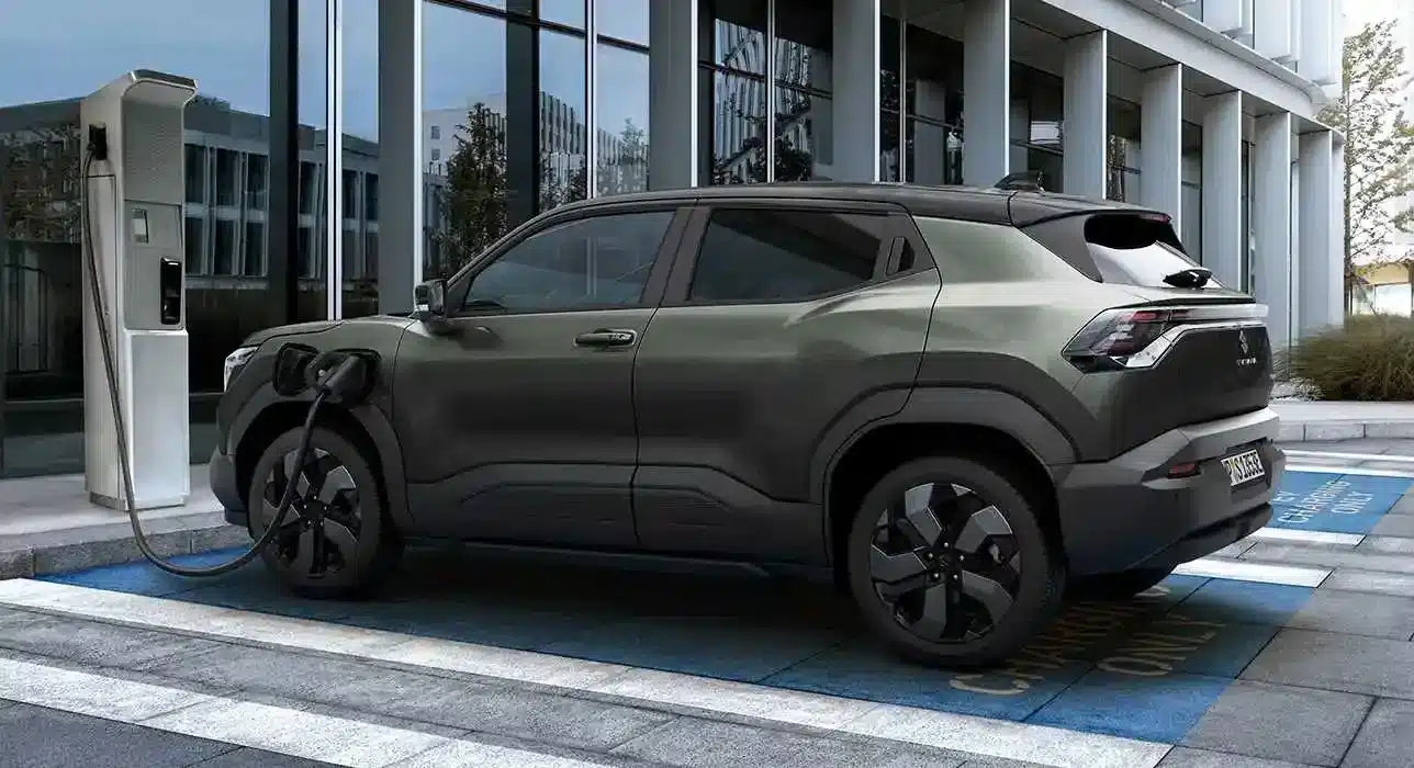 Suzuki e VITARA Elektro-SUV an einer Ladesäule vor einem modernen Bürogebäude.