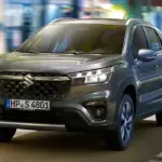 Frontansicht eines grauen Suzuki S-Cross auf einer urbanen Straße.