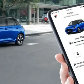 Suzuki Swift 2024 in Blau, im Vordergrund eine Hand mit Smartphone und Swift-App.