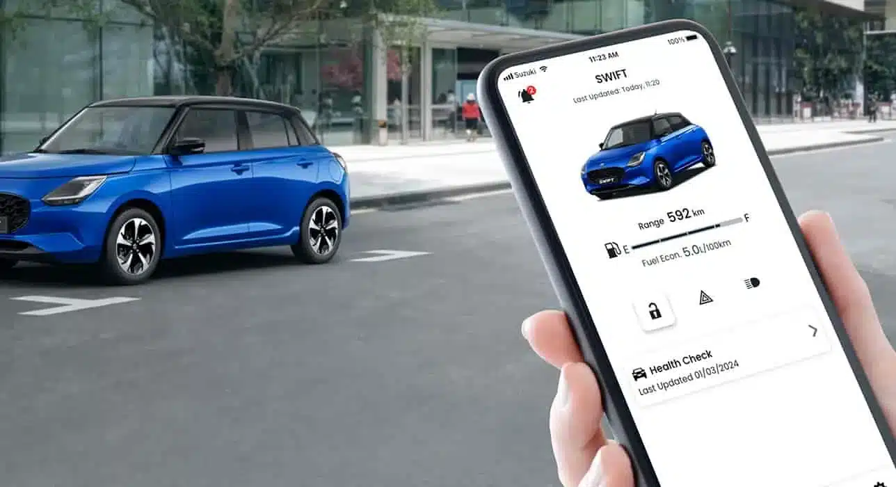 Suzuki Swift 2024 in Blau, im Vordergrund eine Hand mit Smartphone und Swift-App.