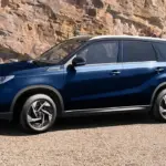 Blauer Suzuki Vitara X-ITE SUV, seitlich geparkt vor Felsen