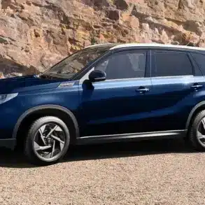 Blauer Suzuki Vitara X-ITE SUV, seitlich geparkt vor Felsen