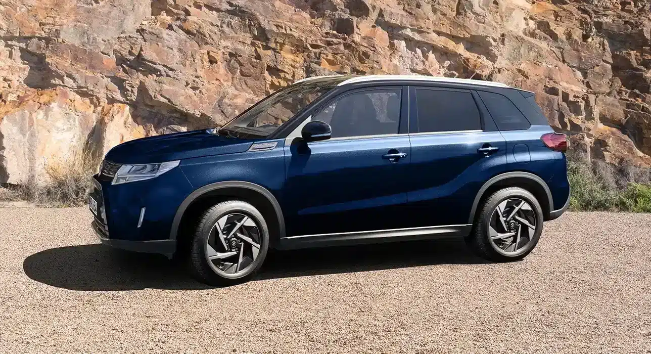 Blauer Suzuki Vitara X-ITE SUV, seitlich geparkt vor Felsen