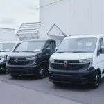 Drei werksseitig umgebaute Renault Nutzfahrzeuge, darunter ein Dreiseitenkipper, vor einem Fabrikgebäude