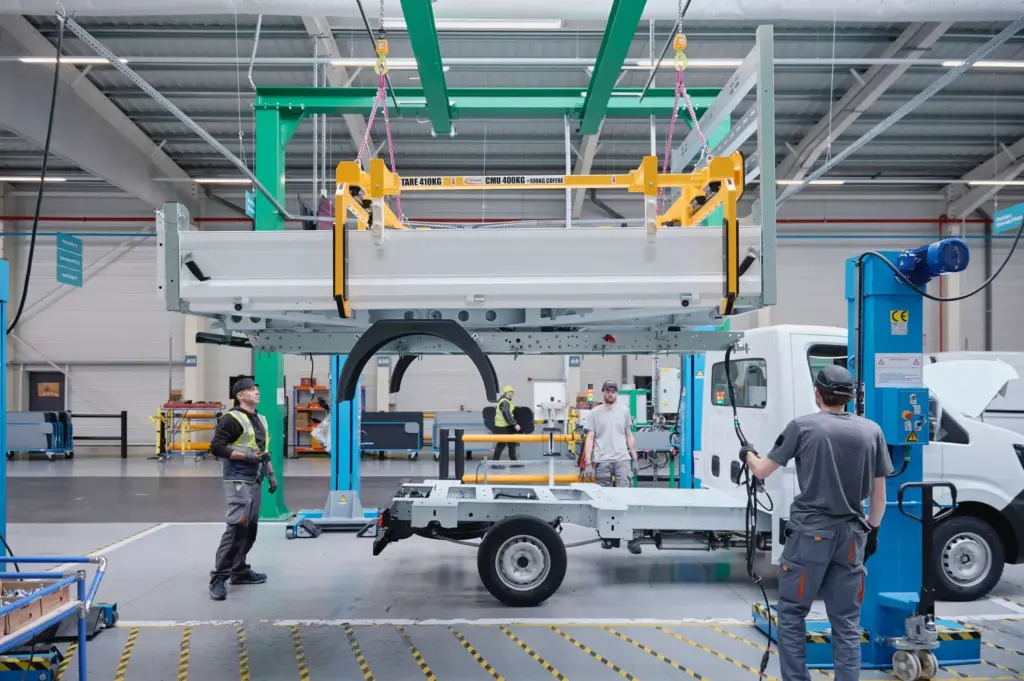 Arbeiter montieren einen Aufbau auf ein Renault Nutzfahrzeug-Chassis in einer modernen Werkshalle