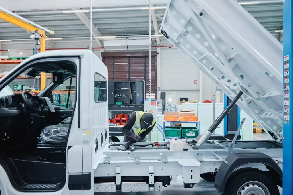 Umbau eines weißen Renault-Nutzfahrzeugs mit Kipper-Aufbau in einer Produktionshalle