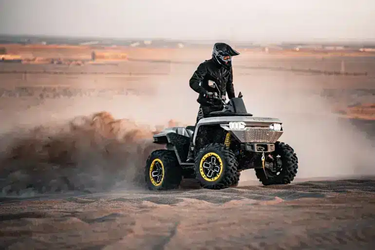 Redstone 550 ATV fährt in sandiger Landschaft und wirbelt Staub auf.