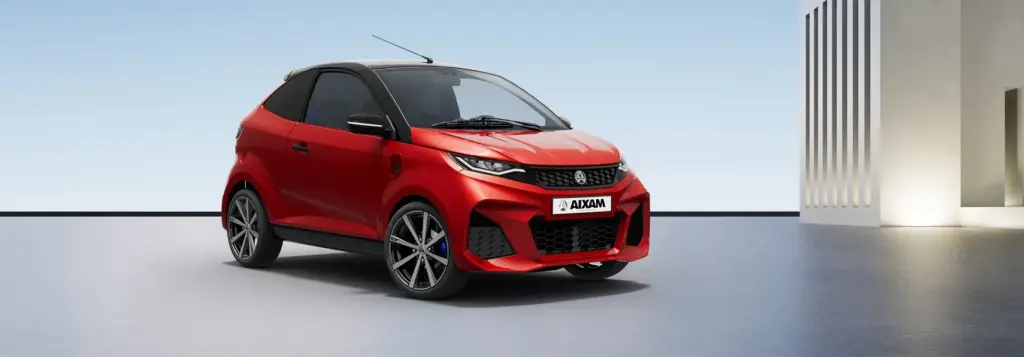 Roter Aixam E Coupé GTi vor modernem Hintergrund, seitliche Frontansicht