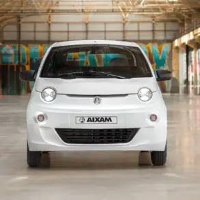 Frontansicht des weißen Aixam Easy Access Diesel in einer Industriehalle mit Graffiti an den Wänden