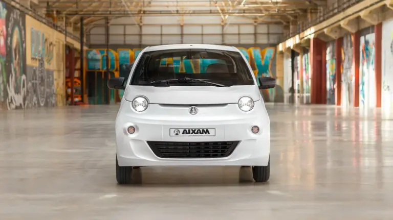 Frontansicht des weißen Aixam Easy Access Diesel in einer Industriehalle mit Graffiti an den Wänden