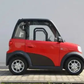 Seitenansicht des roten ARI 802 Elektrofahrzeugs vor einer Mauer, das die kompakten Maße und das zweisitzige Konzept zeigt.